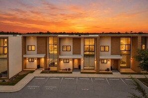A modern hotel with a flat roof, large windows, and a parking lot marked with reserved spaces. - 4 BD/ 4.5 BA/ Magic Village Views (7478 BD) (Kissimmee)