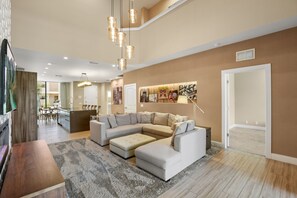 A spacious living room with a sectional sofa, a dining area, and a kitchen in the background. - 4 BD/ 4.5 BA/ Magic Village Views (7478 BD) (Kissimmee)