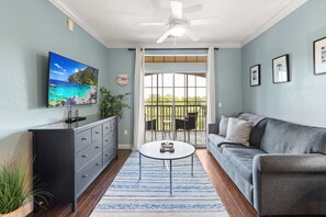 Ein Wohnzimmer mit Sofa, Couchtisch, Fernseher und einem Balkon mit Blick.