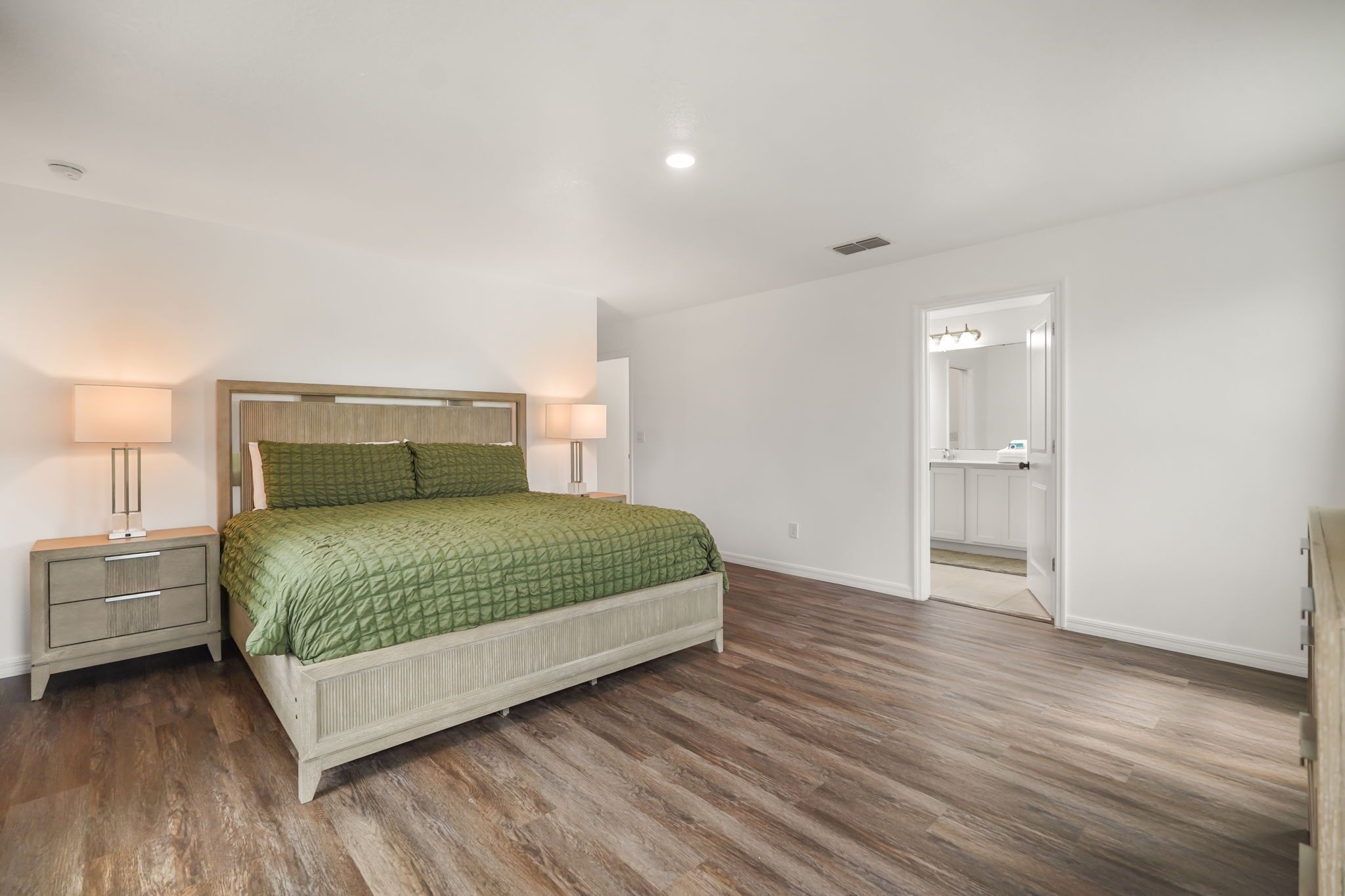 A bedroom with a bed, nightstands, a door, and a small table.