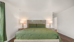 Una camera da letto con un letto, due abat-jour, una testiera e una tenda verde.