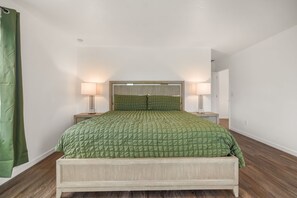 Ein Schlafzimmer mit einem Bett, zwei Nachttischlampen, einer Kopfteil und einem grünen Vorhang.