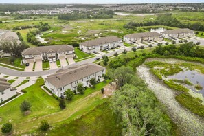 A residential area with multiple two-story houses, a central road, and a small water body. - 3 BD/ 2.5 BA/ The Enclaves at Festival (1773 SD) (Davenport)