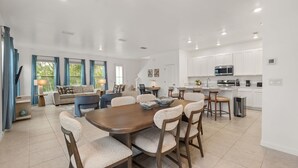 Un soggiorno spazioso con un grande tavolo da pranzo in legno e comodi posti a sedere, una cucina con elettrodomestici moderni e un'atmosfera luminosa e ariosa.