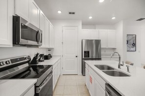 A modern kitchen with white cabinetry, stainless steel appliances, and a double sink. - 3 BD/ 2.5 BA/ The Enclaves at Festival (1773 SD) (Davenport)