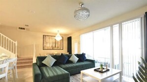 Ein Wohnzimmer mit einem grünen Sofa, einem weißen Couchtisch und einer Chandelier.