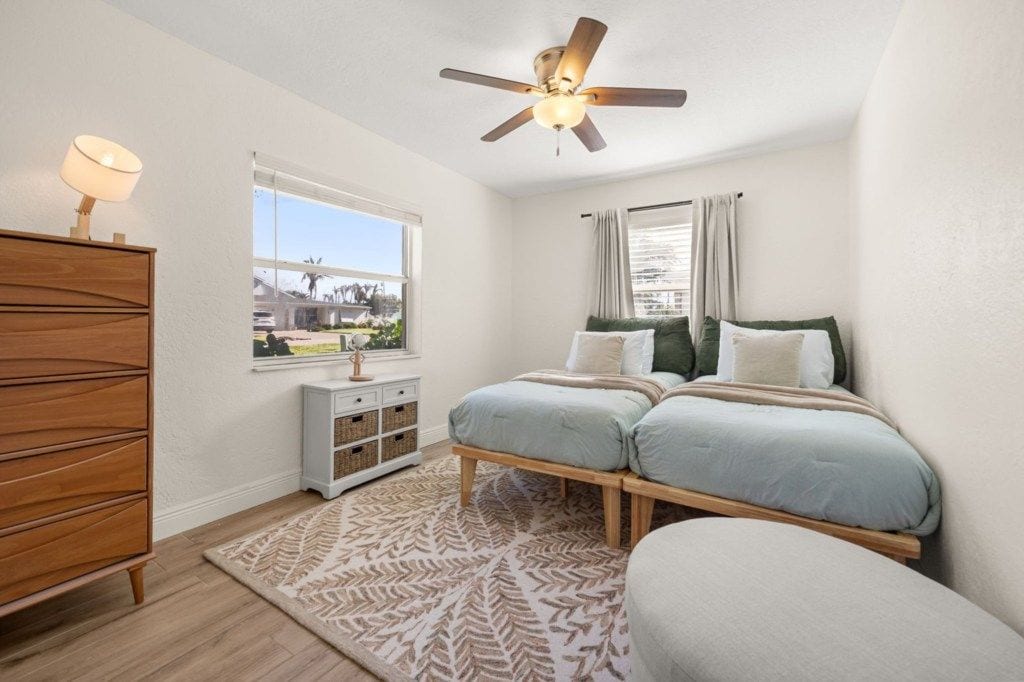 A bedroom with a bed, a ceiling fan, a window, a dresser, and a rug.