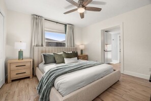 A bedroom with a bed, nightstands, a ceiling fan, and a window with curtains. - Cocoa Beach Oasis: Boho Retreat w/ Huge Yard & Hammock - Sleeps 6 - 125 WG (Cocoa Beach)