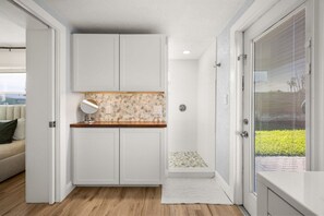 A compact kitchen with white cabinets, a stone backsplash, and a small window. - Cocoa Beach Oasis: Boho Retreat w/ Huge Yard & Hammock - Sleeps 6 - 125 WG (Cocoa Beach)