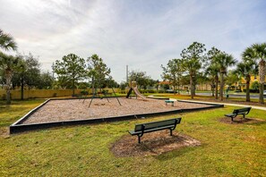 Ein Park mit Spielplatz, Bänken und Bäumen.
