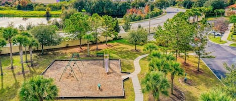 A park with a playground, walking paths, and a body of water in the background.