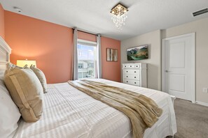 Ein Schlafzimmer mit Bett, Kommode, einem Gemälde und einem Fenster.