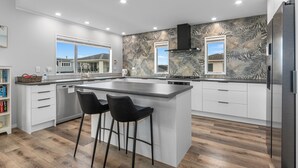 Cozinha moderna com uma ilha grande, banquetas e vista para o exterior.