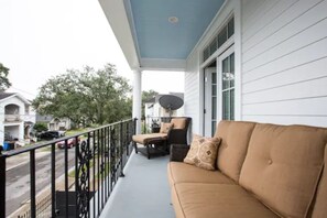 A porch with a beige sofa and two chairs, a satellite dish, and a view of the street. - Maison de l'Artiste | Curated NOLA Stay, Near the FQ (New Orleans)