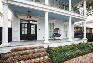 A two-story house with a porch, a front door, and a swing chair. - Maison de l'Artiste | Curated NOLA Stay, Near the FQ (New Orleans)