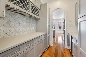 A modern kitchen with grey cabinetry, a patterned backsplash, and a wooden floor. - Maison de l'Artiste | Curated NOLA Stay, Near the FQ (New Orleans)