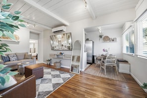 A modern living room with a sofa, coffee table, and a dining area with a table and chairs. - Stylish 2BR Home | Parking & AC | Near Downtown (San Diego)