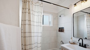 Une salle de bain moderne avec une baignoire, un grand miroir et une fenêtre.