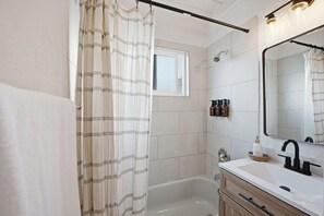 A modern bathroom with a bathtub, a large mirror, and a window. - Stylish 2BR Home | Parking & AC | Near Downtown (San Diego)