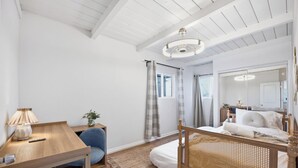 Une chambre à coucher avec un lit en bois, un bureau avec une lampe, une chaise et un grand miroir.