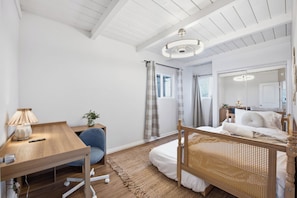 A bedroom with a wooden bed, a desk with a lamp, a chair, and a large mirror. - Stylish 2BR Home | Parking & AC | Near Downtown (San Diego)