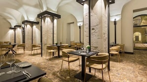 A dining area with tables and chairs, stone pillars, and a vaulted ceiling.
