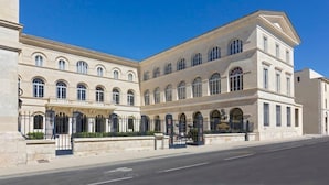 A large, historic building with a symmetrical facade, multiple arched windows, and a central courtyard.