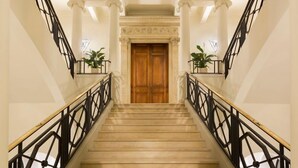 A grand staircase with marble steps, black railings, and a wooden door at the top.