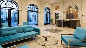 A lobby with a reception desk, two sofas, a coffee table, and large windows.