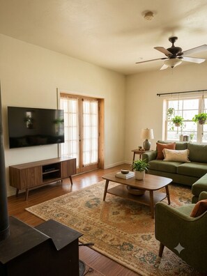 Ein Wohnzimmer mit Flachbildfernseher, Sofa, Couchtisch, Kamin und Deckenventilator.