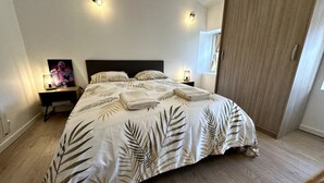 Un dormitorio con cama, mesitas de noche, armario e iluminación en la pared.