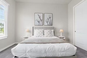 Un dormitorio con cama, dos mesitas de noche, una ventana y dos obras de arte en la pared.