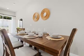 Una mesa de comedor preparada con platos, tazones y tazas, rodeada de sillas.