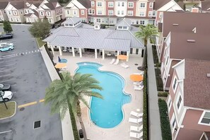Un edificio residencial con piscina, sillas de descanso y aparcamiento.