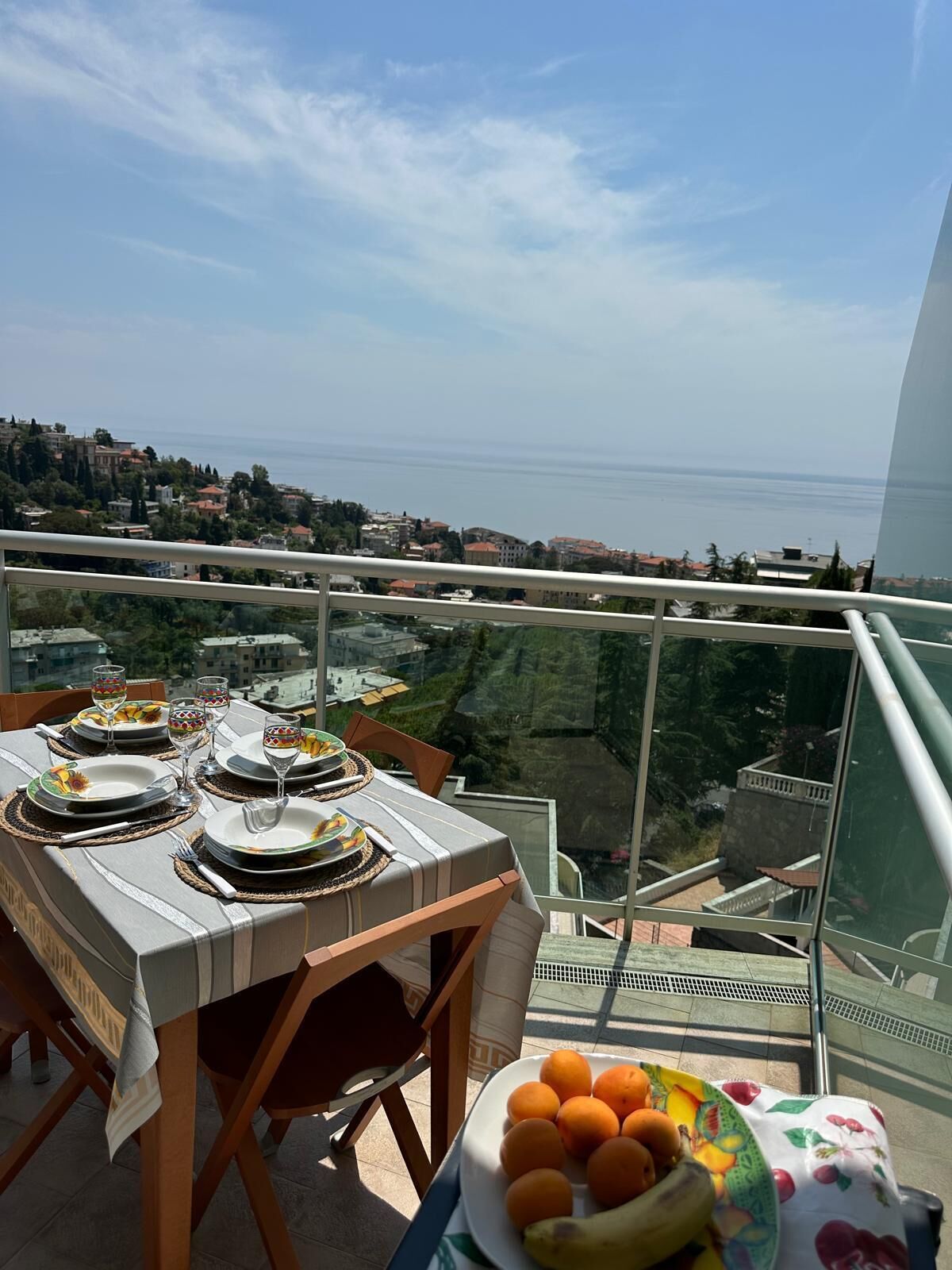 A table set for a meal with a view of the sea and a cityscape.