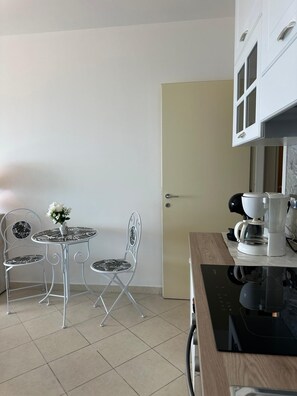 Eine Küche mit Esstisch, zwei Stühlen, einer Kaffeemaschine und einem Schrank.