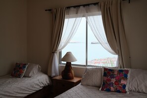 Une chambre avec deux lits, une table de chevet, une lampe et une fenêtre avec des rideaux.