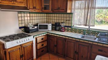 Eine Küche mit einem Bosch-Gasherd, einem Toaster, einer Mikrowelle, einer Kaffeemaschine und einem Mixer.