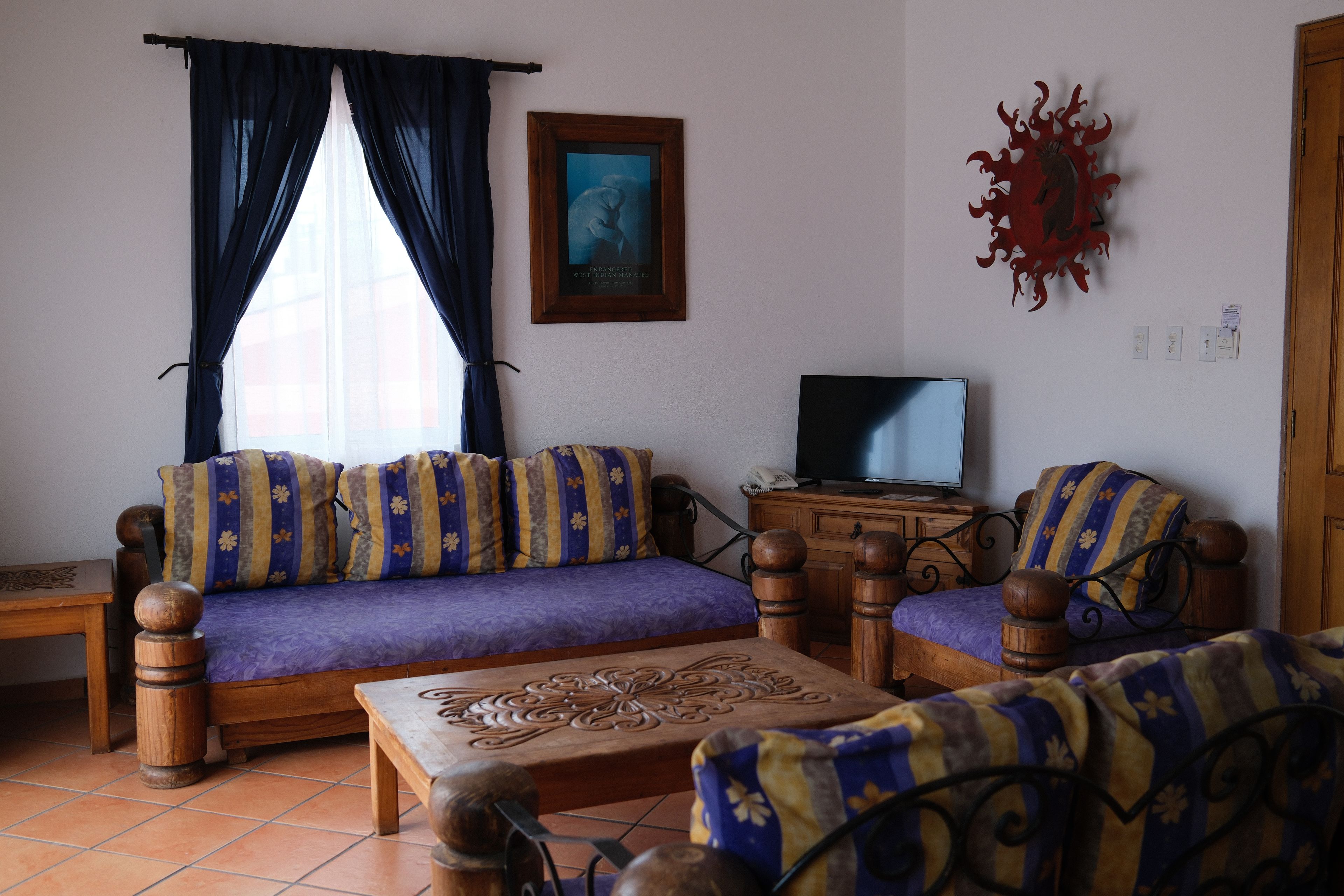 Una sala de estar con un conjunto de sofá, un televisor y un adorno en la pared.