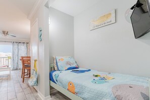 Ein Kinderzimmer mit einem Bett, einem Stuhl, einem Schreibtisch und einem Fenster mit Vorhängen.