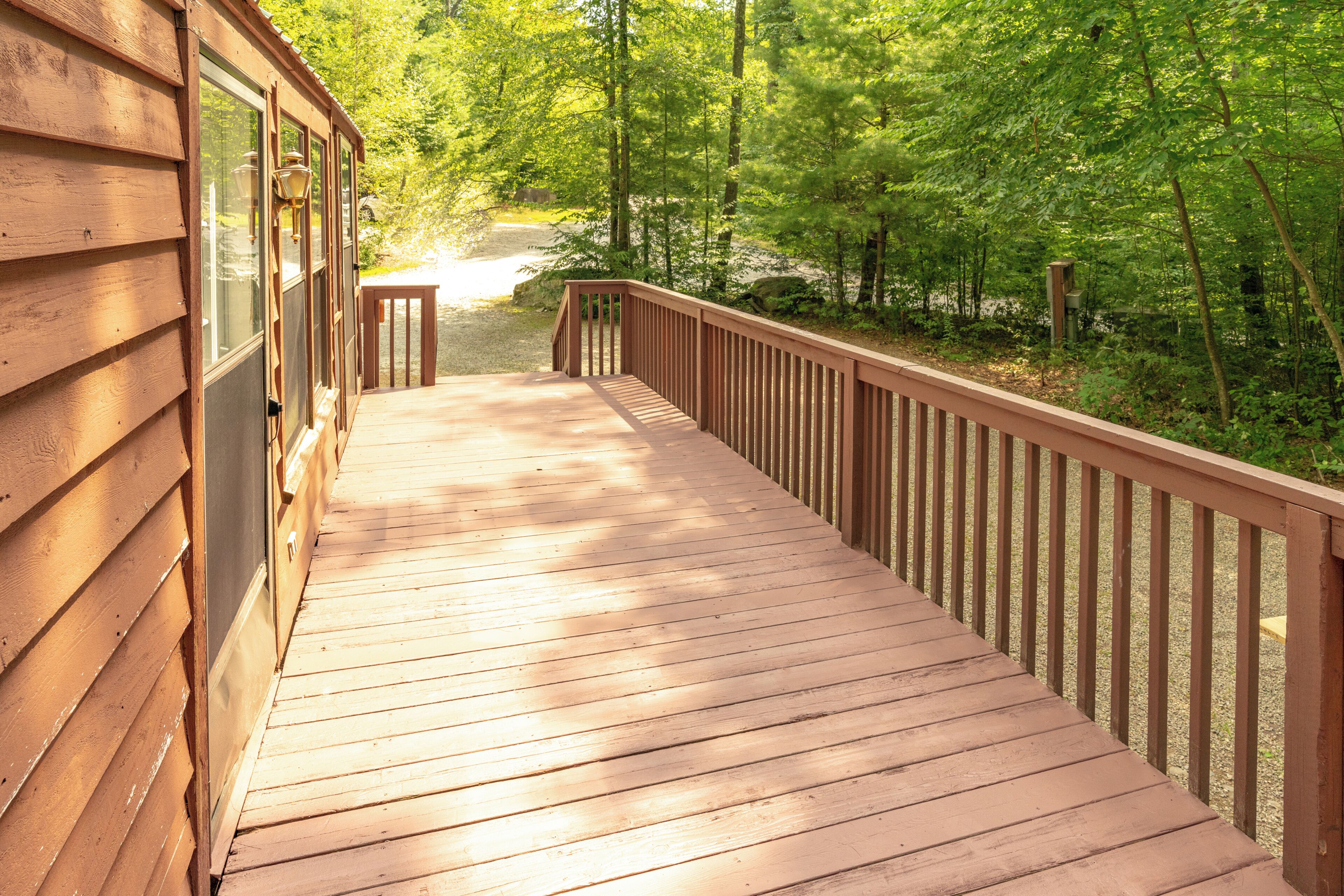 Une terrasse en bois menant à un chalet offrant une vue sur une zone boisée.