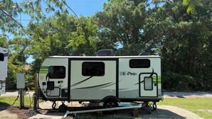 Un camper fermo con un pannello solare, un generatore e una pompa per l'acqua.
