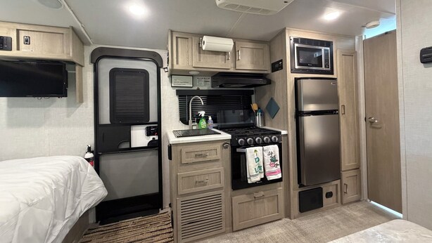 Una cucina compatta per camper, completa di fornelli, lavello, frigorifero e microonde.
