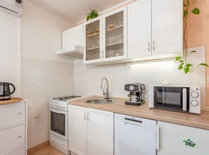 A compact kitchen with white cabinets, a gas stove, a coffee maker, a microwave, and a dishwasher. - One Bedroom Apartment with Terrace (Klana)