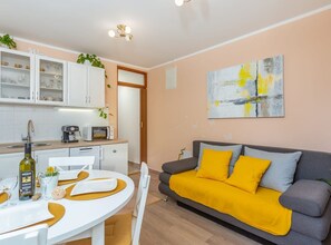 A modern living space with a kitchen, dining area, and a sofa with yellow cushions. - One Bedroom Apartment with Terrace (Klana)