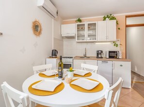 Eine moderne Küche mit weißen Schränken, einer Mikrowelle, einer Kaffeemaschine und einem Essbereich mit einem weißen Tisch und Stühlen.