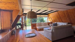 A loft-style room with a wooden table, a sofa, and a hanging light fixture.