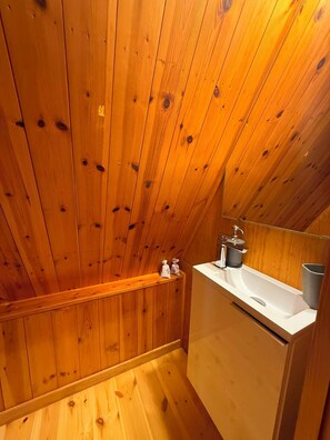 A wooden-paneled bathroom with a sink and a mirror. - Ger's Chalet (Devesa de Saga)