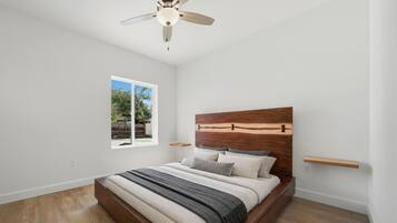 Une chambre à coucher avec une tête de lit en bois, un lit avec plusieurs oreillers, une fenêtre et un ventilateur de plafond.