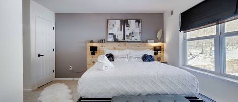 Une chambre à coucher avec un lit, une table de chevet, une commode, une fenêtre et une porte.